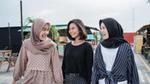 Tiga wanita tersenyum dan berjalan di luar ruangan.